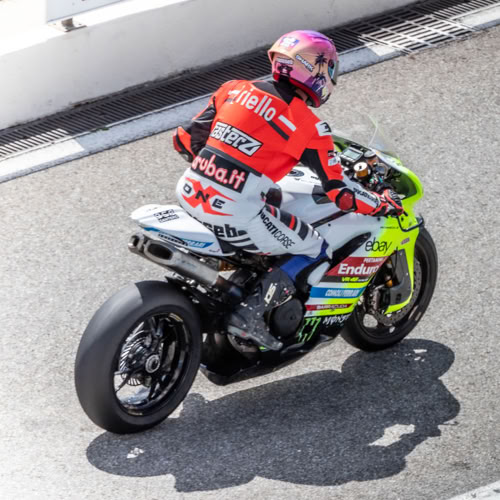 Circuit Paul Ricard Motard en combinaison rouge et casque rose sur une moto de course.